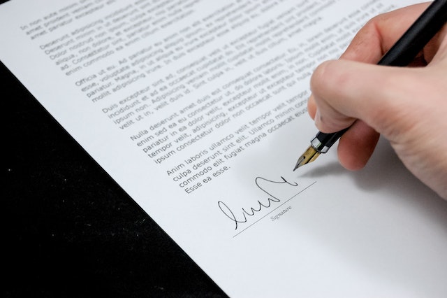 person%20signing%20a%20contract%20with%20a%20black%20fountain%20pen
